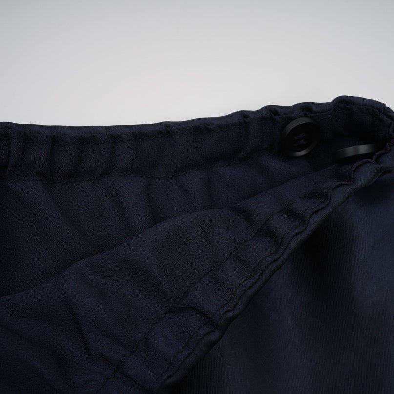 A woman wearing a long blue maxi dress with a fitted peplum waist and panelled design standing in a relaxed pose