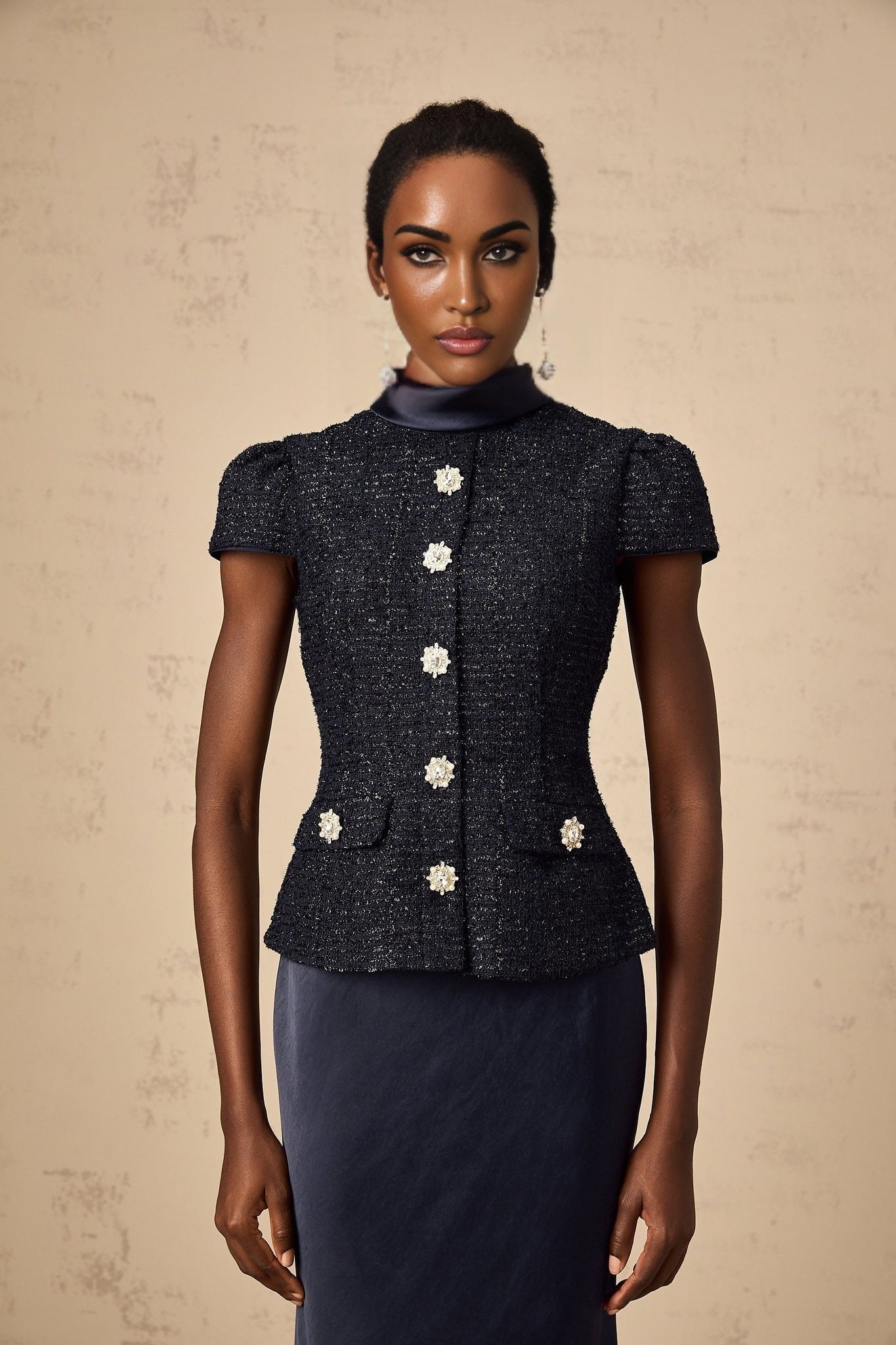 A woman wearing a long blue maxi dress with a fitted peplum waist and panelled design standing in a relaxed pose