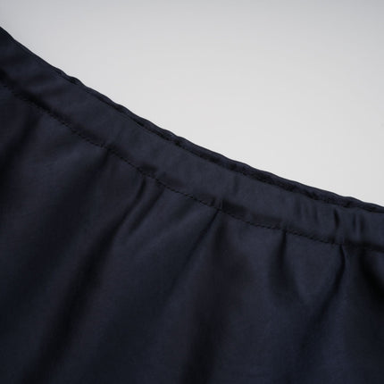 A woman wearing a long blue maxi dress with a peplum waist and panelled design standing in a neutral background