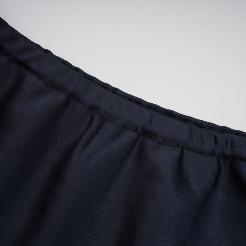 A woman wearing a long blue maxi dress with a peplum waist and panelled design standing in a neutral background