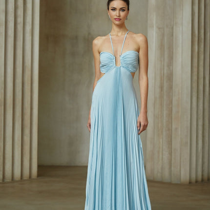 A woman wearing a long blue pleated maxi dress with a cutout detail standing against a plain background