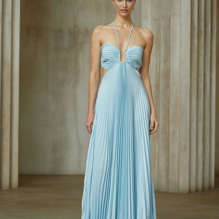 A woman wearing a long blue pleated maxi dress with a cutout detail standing against a plain background