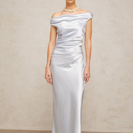 A woman wearing a long blue satin maxi dress with off the shoulder sleeves and ruched detailing