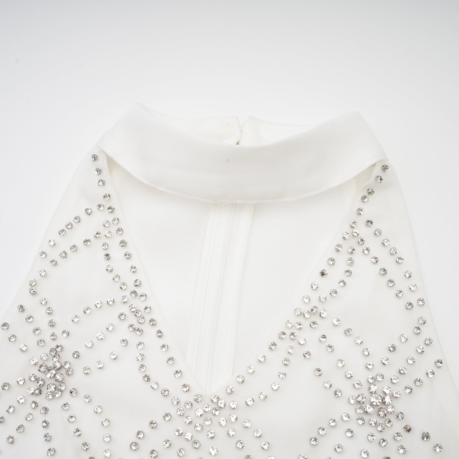 A woman wearing a long elegant Magdalena dress with intricate embellishments and embroidery details