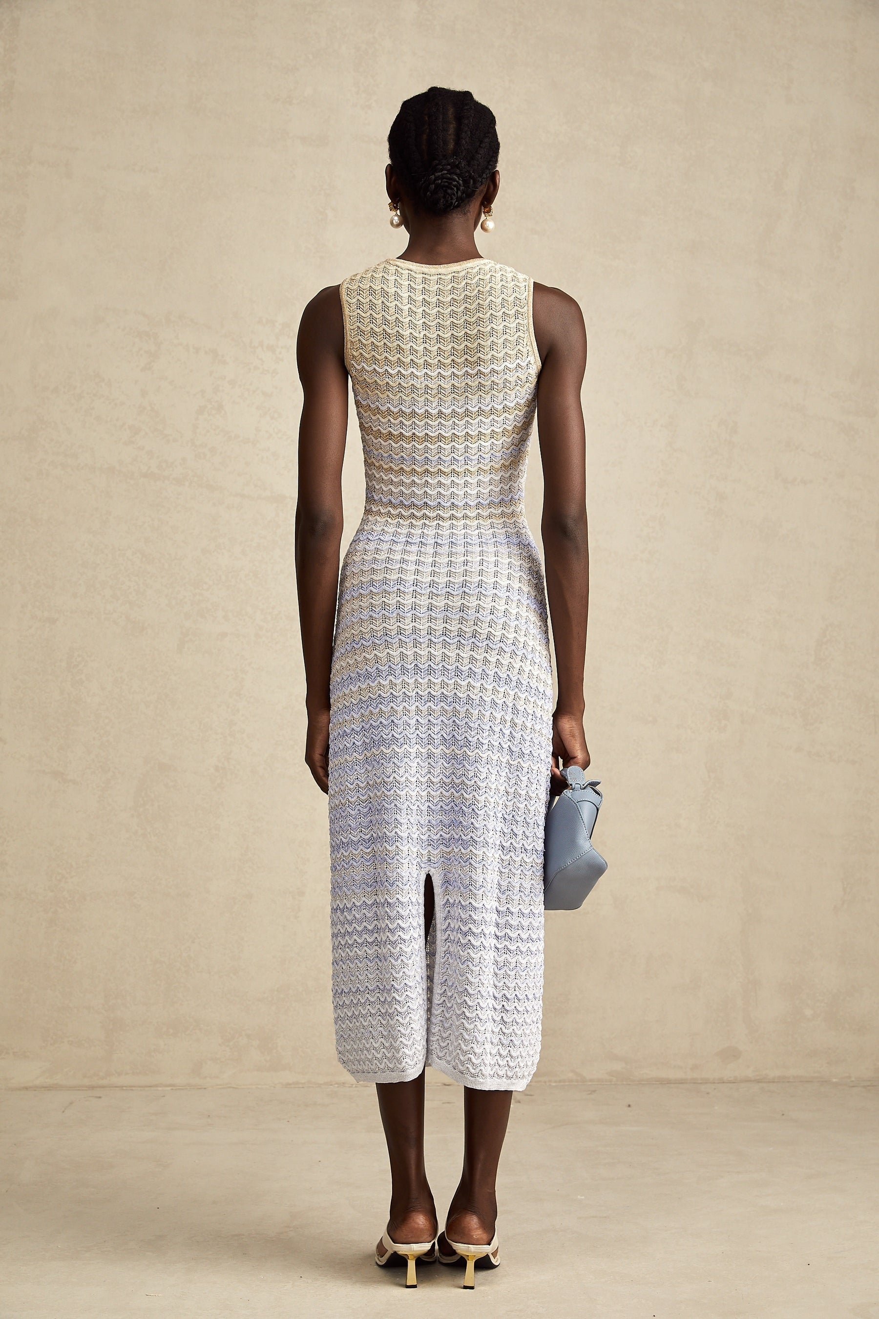 A woman wearing a long fitted ribbed knit dress with contrasting color panels and a midi length skirt