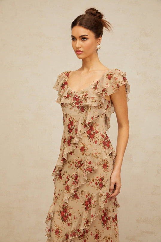 A woman wearing a long floral print maxi dress with ruffles and a flared skirt