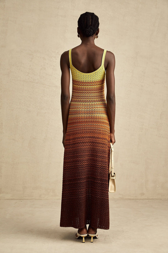 A woman wearing a long flowing knitted maxi dress with a gradient color pattern named Audrey