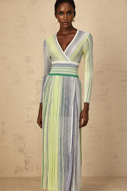A woman wearing a long green maxi dress with long sleeves and vertical sequin stripes standing in a relaxed pose