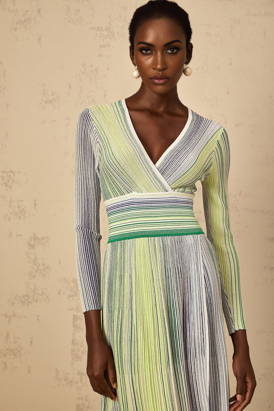 A woman wearing a long green maxi dress with long sleeves featuring sequin stripes and a knit fabric