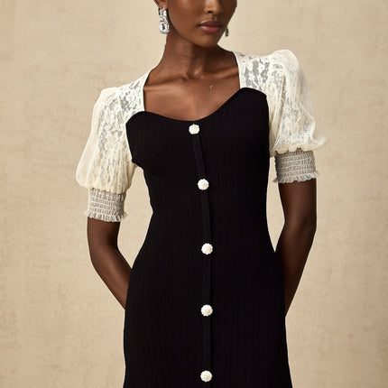 A woman wearing a long knit midi dress with lace trim details along the neckline and hem standing in a relaxed pose against a plain background