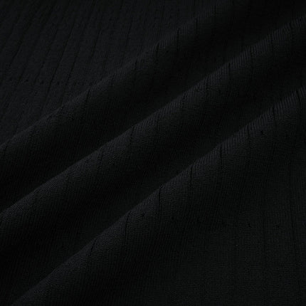 A woman wearing a long knit midi dress with lace trim details at the neckline and hem standing in a neutral background