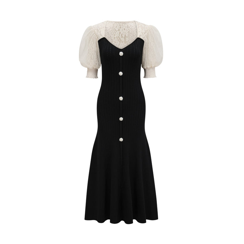 A woman wearing a long knit midi dress with lace trim details at the neckline and hem standing in a neutral pose against a plain background