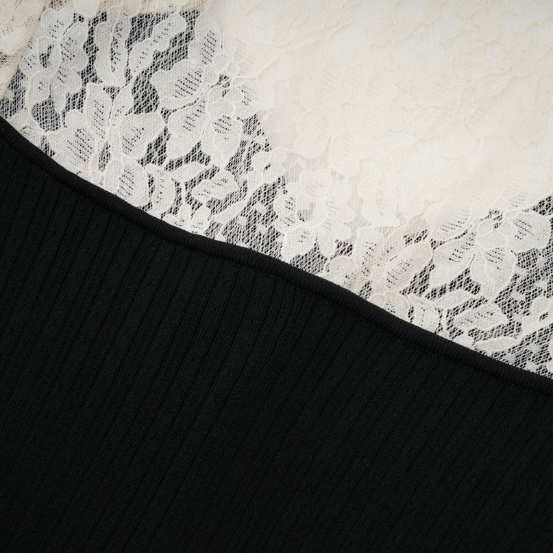 A woman wearing a long knit midi dress with lace trim details at the neckline and hem standing in a neutral pose against a plain background