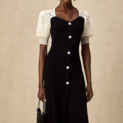 A woman wearing a long knit midi dress with lace trim details standing against a neutral background