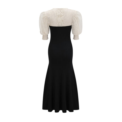 A woman wearing a long knit midi dress with lace trim details standing in a neutral setting