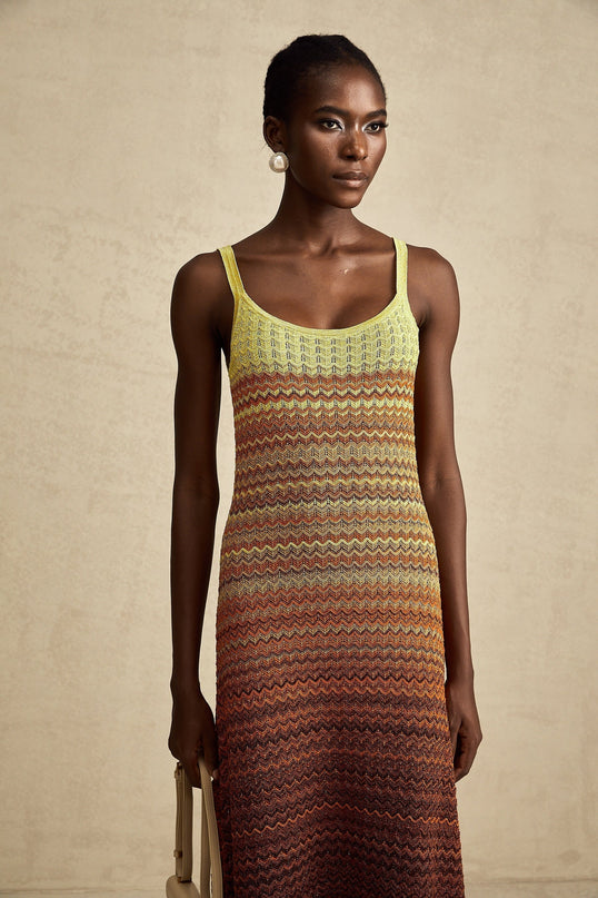 A woman wearing a long knitted maxi dress with a gradient color pattern named Audrey standing in a casual pose