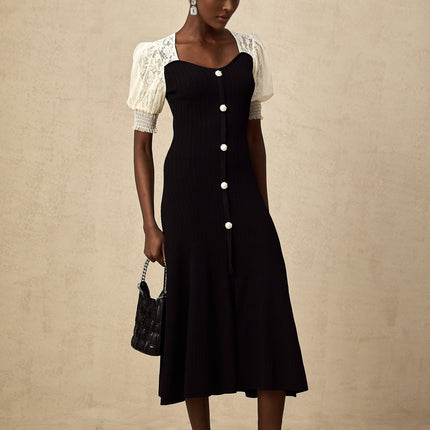 A woman wearing a long knitted midi dress with lace trim details standing in a relaxed pose