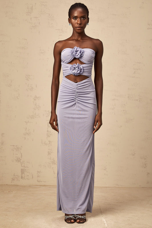 A woman wearing a long lavender dress with a fitted corset bodice and ruched 3D petal details on the skirt