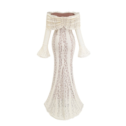 A woman wearing a long neutralcolored floral lace maxi dress with a train design standing in an elegant pose