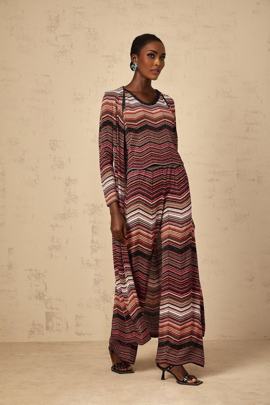 A woman wearing a long red cardigan with white stripes knitted in a soft fabric The cardigan has an open front and falls below the knees