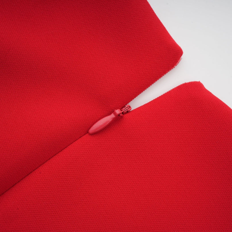 A woman wearing a long red dress with floral patterns and long sleeves