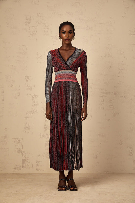 A woman wearing a long red maxi dress with long sleeves and vertical sequin stripes knitted into the fabric