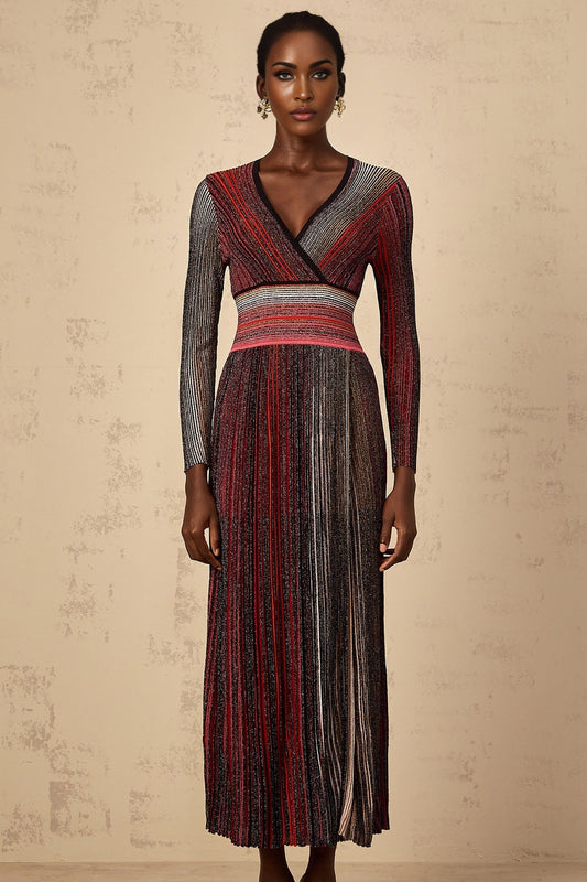 A woman wearing a long red maxi dress with long sleeves and vertical sequin stripes standing against a plain background