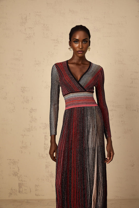 A woman wearing a long red maxi dress with long sleeves and vertical sequin stripes the dress has a knit texture and falls to the floor