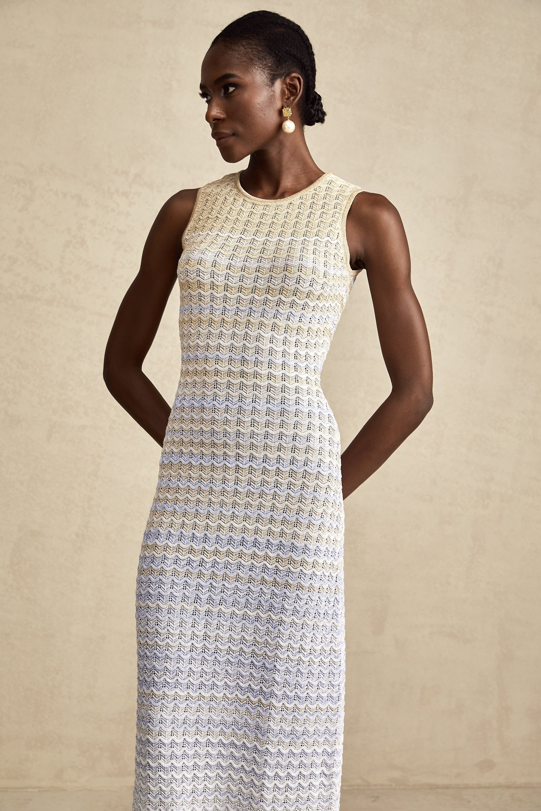 A woman wearing a long ribbed knit dress with contrasting colors featuring a fitted silhouette and midi length
