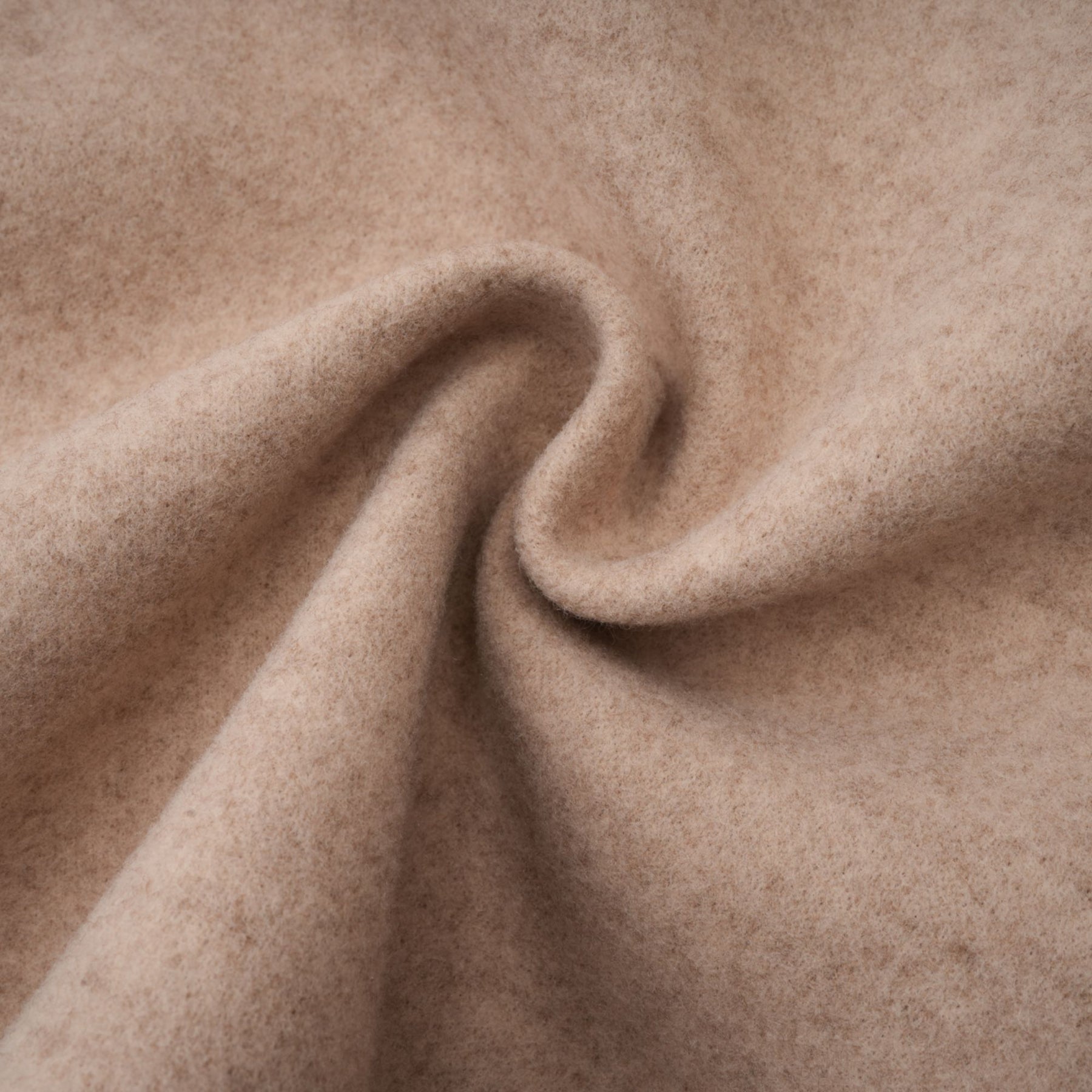 A woman wearing a long white faux fur coat with a detachable cape collar standing against a plain background