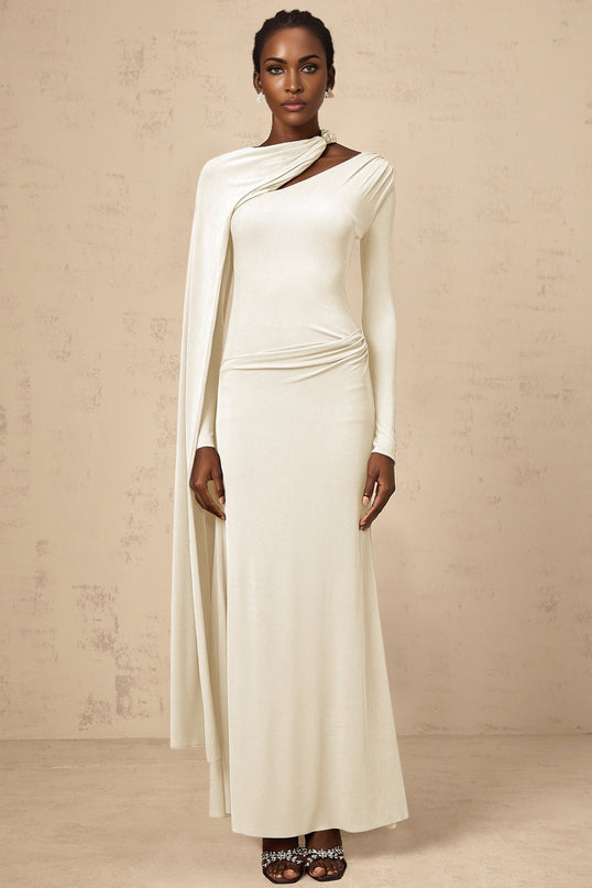 A woman wearing a long white fitted maxi dress with a diagonal shawl neckline standing in a neutral pose