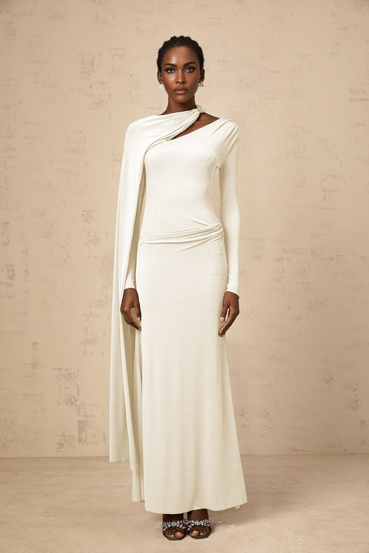A woman wearing a long white fitted maxi dress with a diagonal shawl neckline
