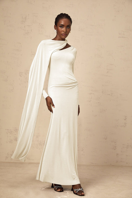 A woman wearing a long white fitted maxi dress with a diagonal shawl neckline