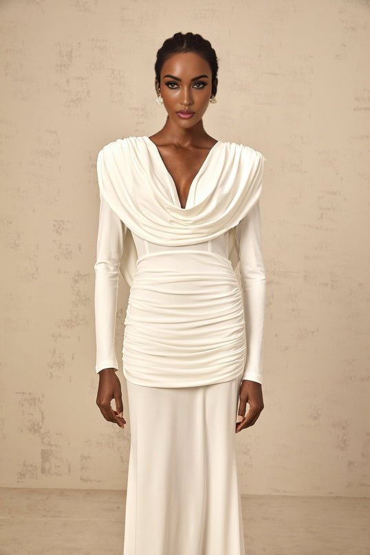 A woman wearing a long white fitted maxi dress with ruched detailing along the body standing in a neutral pose against a plain background