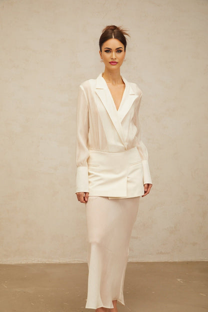 A woman wearing a long white flowy maxi dress with sheer panels standing in a relaxed pose