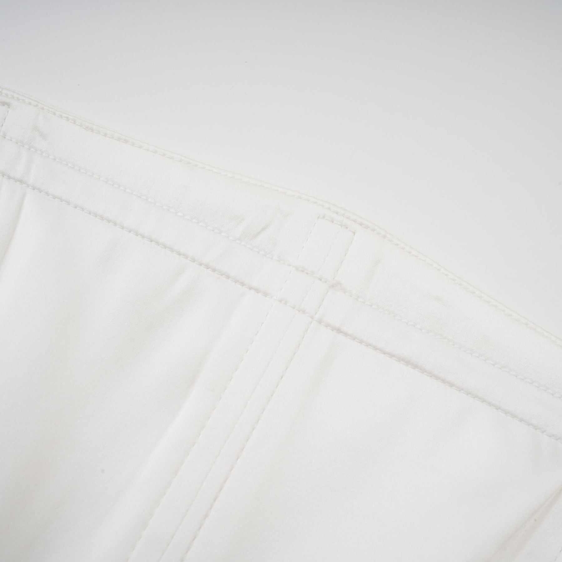 A woman wearing a long white pleated maxi dress with an offshoulder neckline