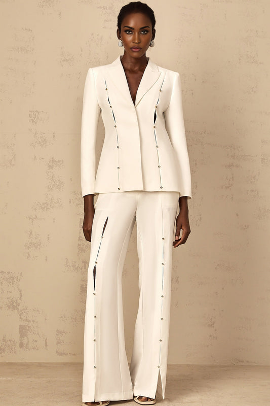 A woman wearing a matching blazer and trouser pant set with embellishments named Frida The outfit features a tailored blazer and slim fit pants in a coordinated fabric with decorative details