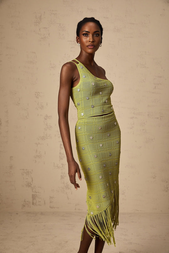 A woman wearing a matching green knit top and skirt set The top features embellishments and the outfit is named Annette The ensemble has a coordinated look suitable for formal occasions