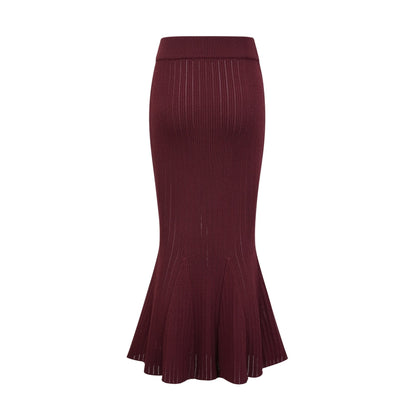 A woman wearing a matching red knit outfit consisting of a ruffled top and skirt The top has short sleeves and the skirt falls to mid thigh length The set is called Corrine and has a vibrant red color