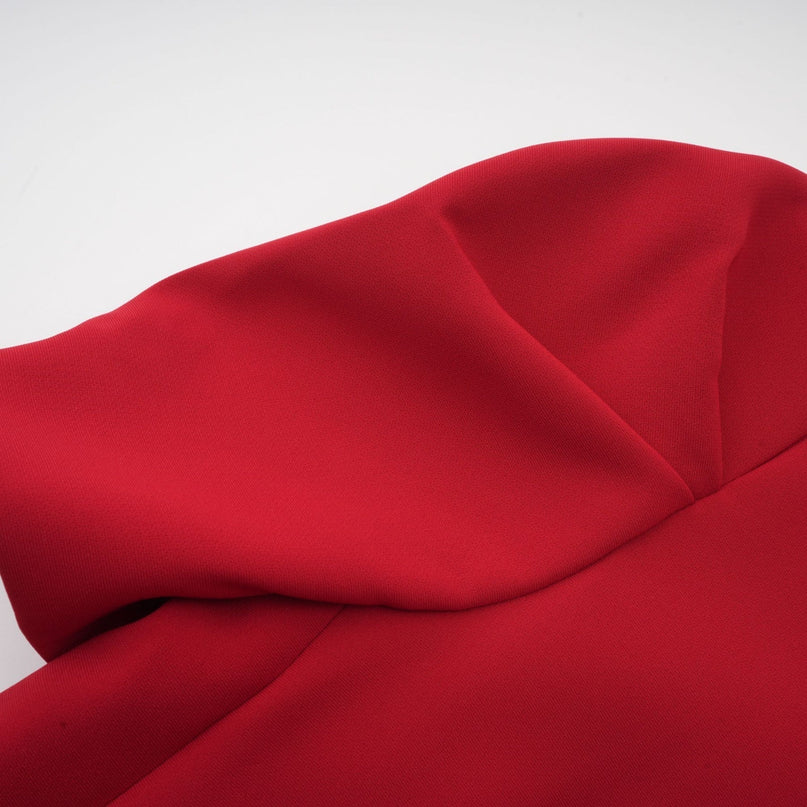 A woman wearing a matching red outfit consisting of a pleated blouse and skirt The blouse has a collar and short sleeves while the skirt falls to about knee length Both pieces feature pleated fabric in a vibrant red color