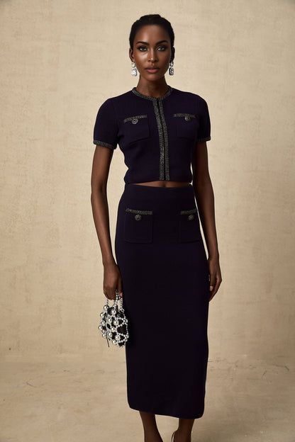 A woman wearing a matching ribbed knit top and skirt set in a light color The top is sleeveless with embellishments and the skirt is knee length Both pieces feature a textured knit pattern