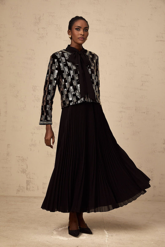 A woman wearing a matching sequined cardigan and dress set in a checkered pattern The outfit is sparkly and elegant suitable for formal occasions