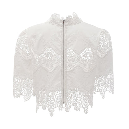 A woman wearing a matching set consisting of a cropped top and trousers in white The top features lace trim and cutout details The trousers are high waisted and flared The model poses against a plain background