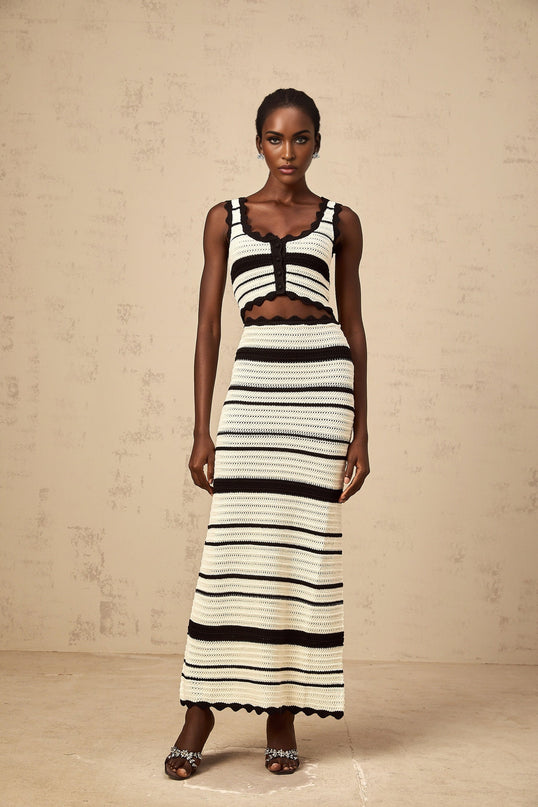 A woman wearing a matching set consisting of a striped vest top and skirt The top features contrasting colors and a sleeveless design The skirt is coordinated with the top creating a cohesive outfit look