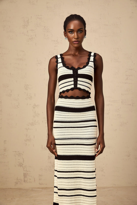 A woman wearing a matching set consisting of a striped vest top and skirt The top features contrasting colors and is sleeveless The skirt is in a coordinating color The outfit has a stylish and casual summer look