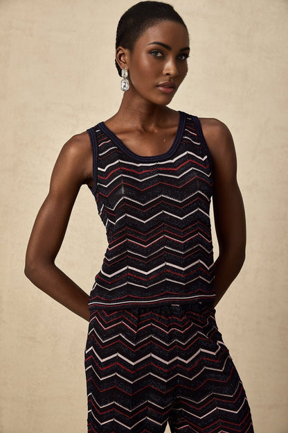 A woman wearing a matching set consisting of a zigzag patterned crochet knit top and trousers in a light color The top has short sleeves and the trousers are wide legged The set has a bohemian summer style