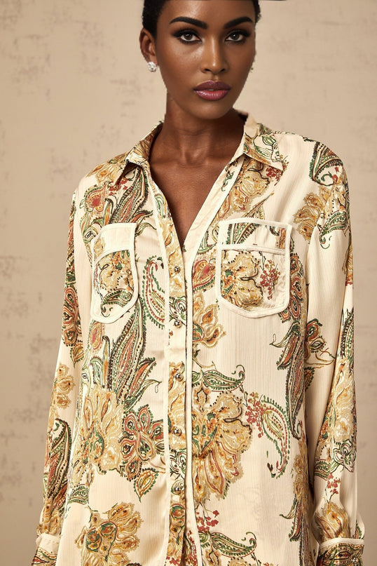 A woman wearing a matching set of lightcolored shirt and trousers with a delicate floral print pattern