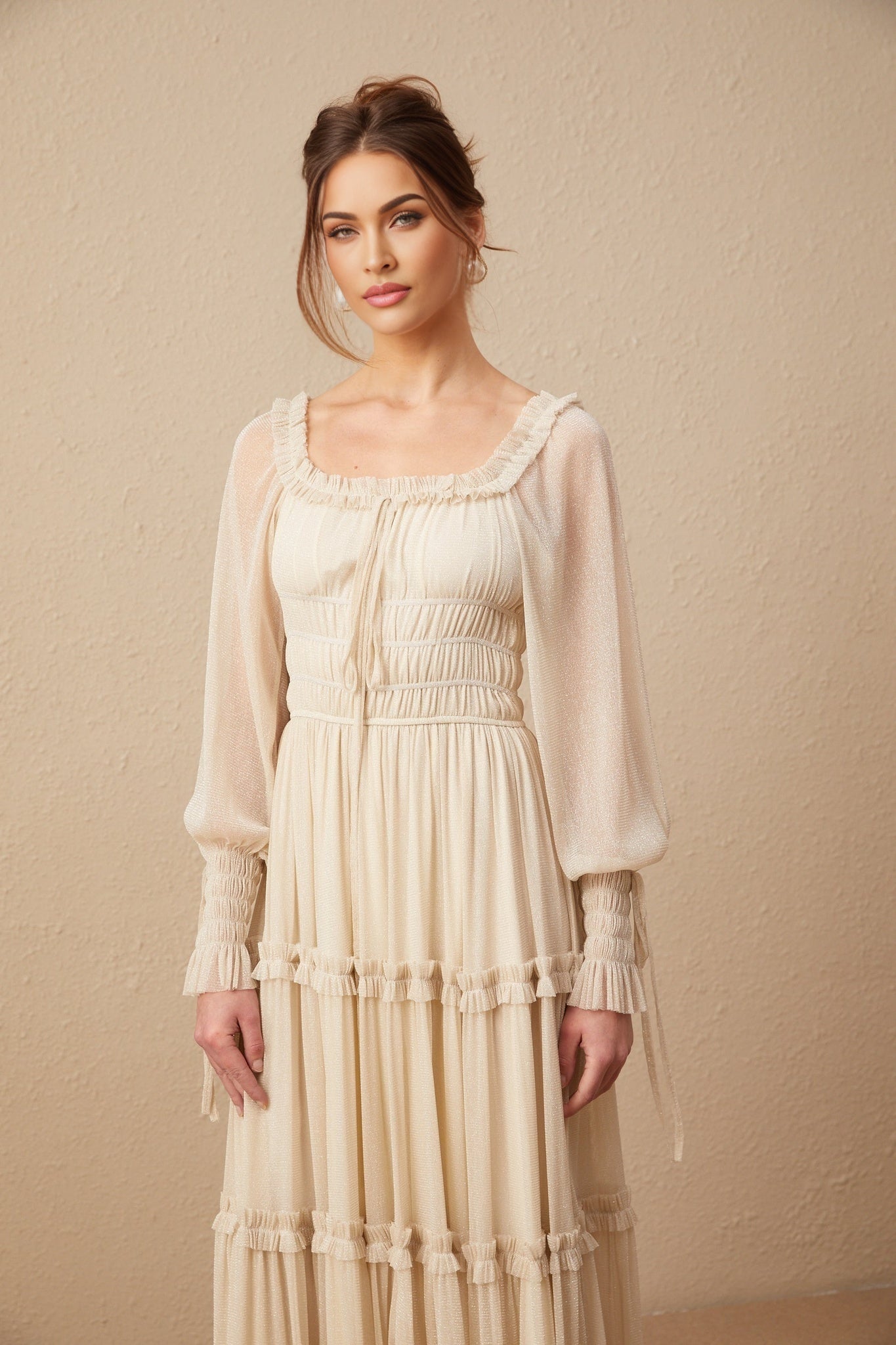 A woman wearing a metallic pleated midi dress with shirred detailing and a flowy skirt named Camille