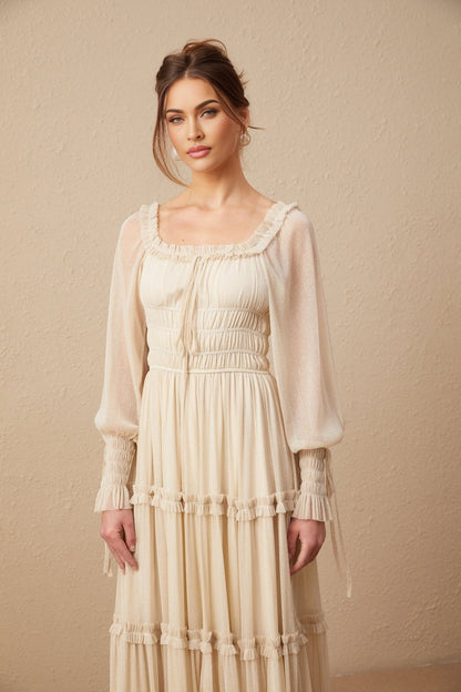 A woman wearing a metallic pleated midi dress with shirred detailing and a flowy skirt named Camille