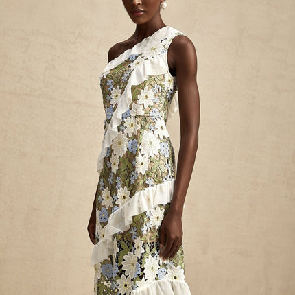 A woman wearing a midi length dress with floral embroidery in pastel colors standing against a light background